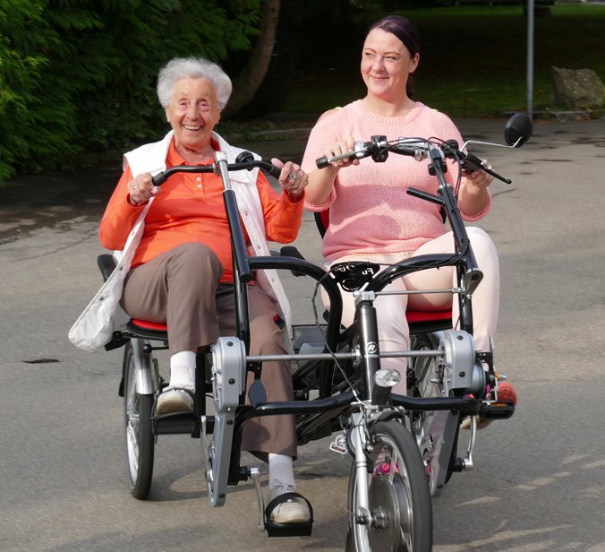 Senorin und Pflegerin fahren auf Tandem